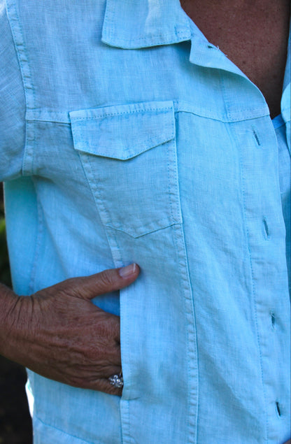 Close-up of a pistachio green jacket with a hand on the chest pocket.