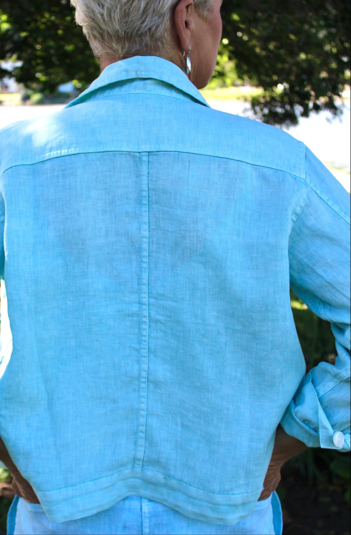 Person wearing a pistachio green jacket outdoors with greenery in the background
