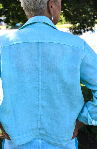 Person wearing a pistachio green jacket outdoors with greenery in the background